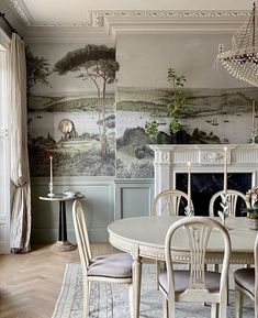 a dining room table with chairs and a chandelier in front of a fireplace