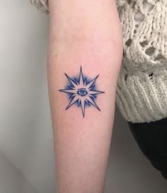 a woman's arm with a blue tattoo on it and an all seeing eye