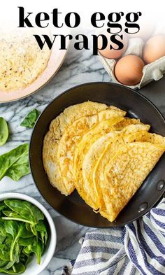 keto egg wraps in a skillet with spinach and eggs on the side