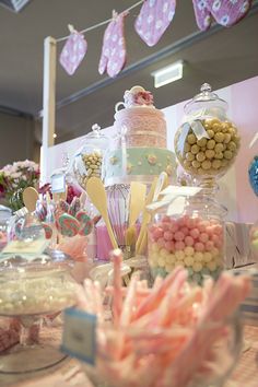 a table filled with lots of candy and candies on top of glass dishes next to bunting