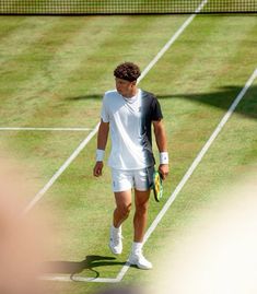 a tennis player walks on the court with his racket