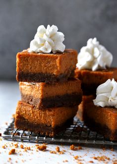 four pieces of cake sitting on top of a cooling rack with whipped cream and chocolate