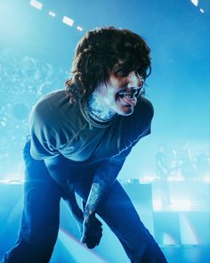 a man with long hair and piercings on his face standing in front of a stage