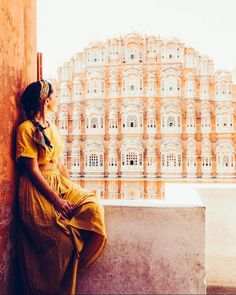 a woman sitting on a ledge in front of a building