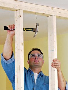 a man holding a hammer in his hand while looking through the hole in the wall