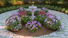 a fountain surrounded by flowers in the middle of a brick walkway with a bench in the background