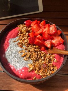 a bowl filled with yogurt, granola and strawberries