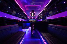 the inside of a bus with purple lights and black seats on it's sides