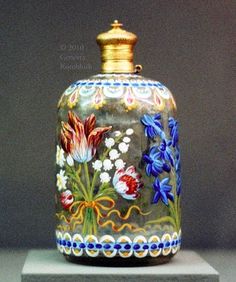 a vase with flowers painted on it sitting on top of a white pedestal in front of a gray wall