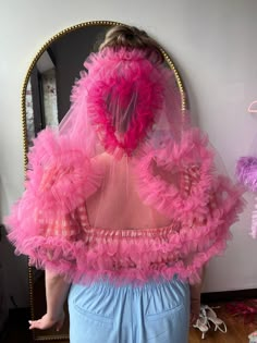 a woman in pink and blue is looking at herself in the mirror with her back to the camera