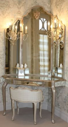 a dressing table with a mirror, stool and chandelier