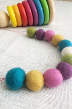 a multicolored felt bead necklace with wooden beads on a white fabric background