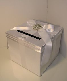 a white gift box with a bow and diamond brooch sits on a countertop