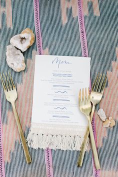 a table setting with silverware and menu cards on it, along with gold utensils