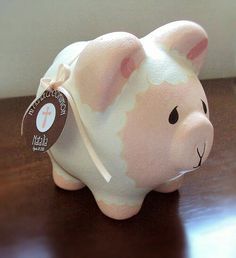 a pink and white ceramic pig sitting on top of a wooden table next to a wall