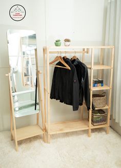 a clothes rack and mirror in front of a white wall with a shelf next to it