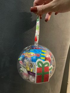 a hand holding a plastic ornament with candy and candies on the inside