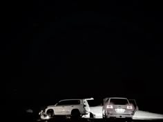 two cars parked on the side of a road at night with one being pulled over