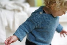 a toddler in a blue sweater playing with a toy