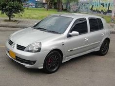 a silver car parked in front of a wall with graffiti on it's side