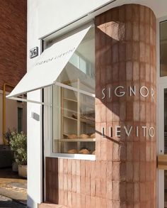 a sign for a bakery on the side of a building with glass doors and windows