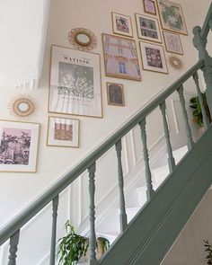 there are many framed pictures on the wall next to the bannister and stairs