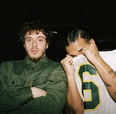 two men with tattoos on their arms and one is holding a football jersey over his head