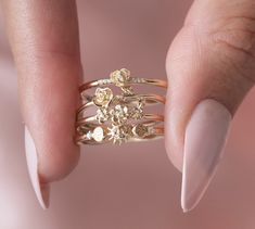 a woman's hand with white nails and gold rings on her fingers, holding onto the