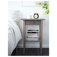 a nightstand with magazines on it next to a bed