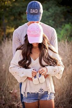 a man and woman standing next to each other with their arms around one another while wearing baseball caps