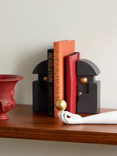 a pair of scissors sitting on top of a wooden shelf next to books and a vase