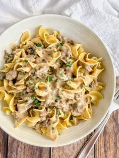 a white bowl filled with pasta covered in gravy on top of a wooden table