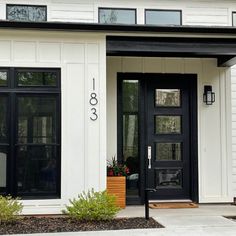 the front door of a white house with black trim and glass windows on both sides