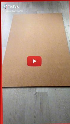 an open cardboard box on the floor with a red border around it and a video play button