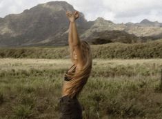 a woman reaching up into the air to catch a frisbee in her hand