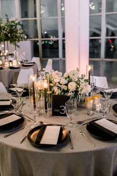 the table is set with silverware, candles and flower centerpieces for an elegant wedding reception