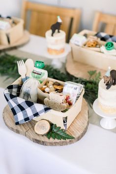 a table topped with cakes and desserts on top of wooden trays covered in greenery