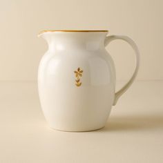 a white pitcher with gold trim on the handle