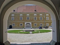 an archway leading to a large building with cars parked in the driveway