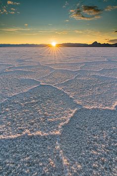 the sun is setting over an icy lake