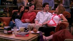 three people sitting on a couch in front of a table with coffee cups and books