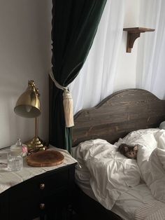 a cat laying on top of a white bed in a bedroom next to a window