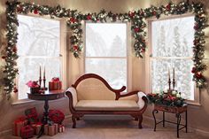 a living room decorated for christmas with presents on the floor and candles in the windows