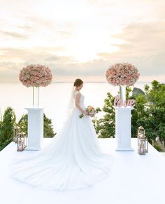 a woman in a wedding dress is standing on a white platform with flowers and lanterns