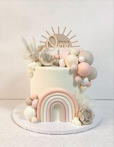 there is a white cake with pink and gold decorations on it, including a rainbow