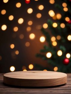 a wooden plate sitting on top of a table next to a christmas tree with lights in the background