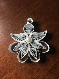 an ornament made out of paper on a wooden table with a pearl in the center