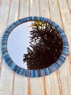 a round mirror on the side of a wooden wall with a tree in it's reflection