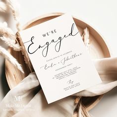 an elegant wedding card with the word we're engaged written on it sitting on a plate