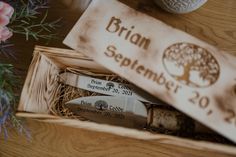 two knives in a wooden box on a table next to some flowers and a sign